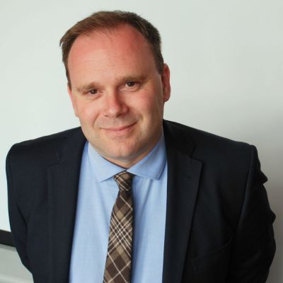 a head and shoulders of a smiling man in a suit and tie