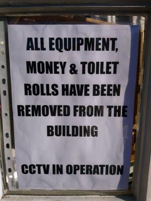 a sign in a window reading money, equipment and toilet rolls removed from this building
