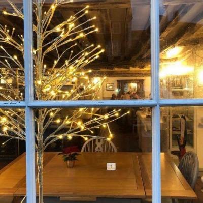 looking into a building through a window, an empty restaurant table is reserved while in the background people are eating. click or tap to open an article list places to eat at Christmas