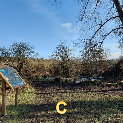 a countryside scene. An information board is on the left. A muddy path leads to trees and a river