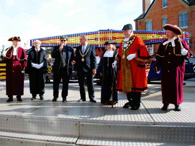 a group of people in formal robes stand on a fairground ride