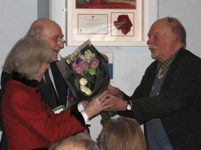 two men and woman shake hands and pass flowers