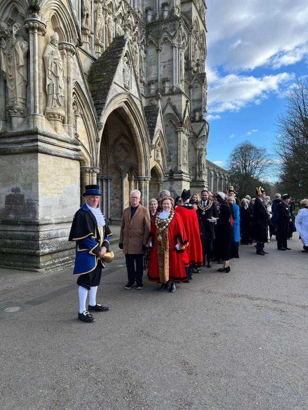 ROL-procession people in ceremonial robes stand outside an ornately carved stone building