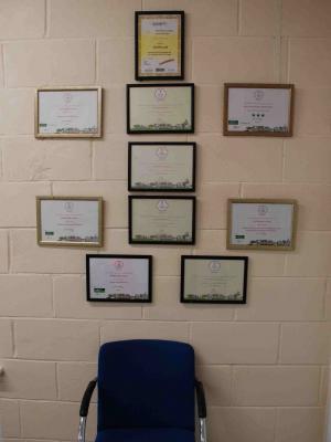 framed certificates on a wall above a chair