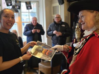 Two women each hold one side of a document
